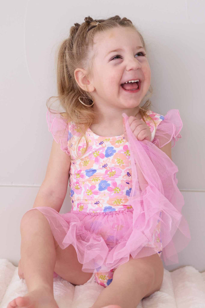 girl holding skirt wearing floral leotard