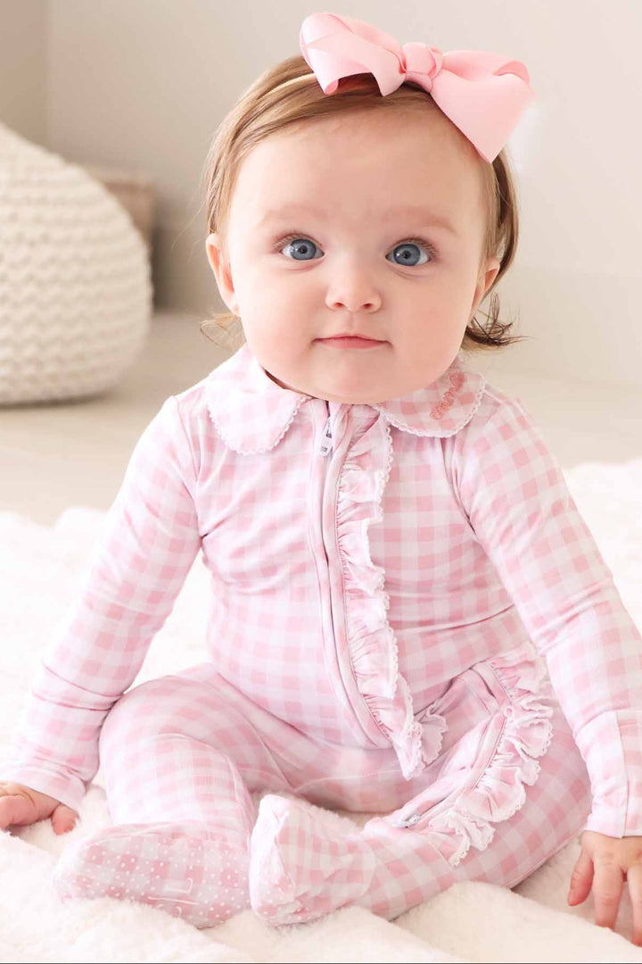 baby girl wearing light pink gingham print footie with lace trim and embroidered peter pan collar