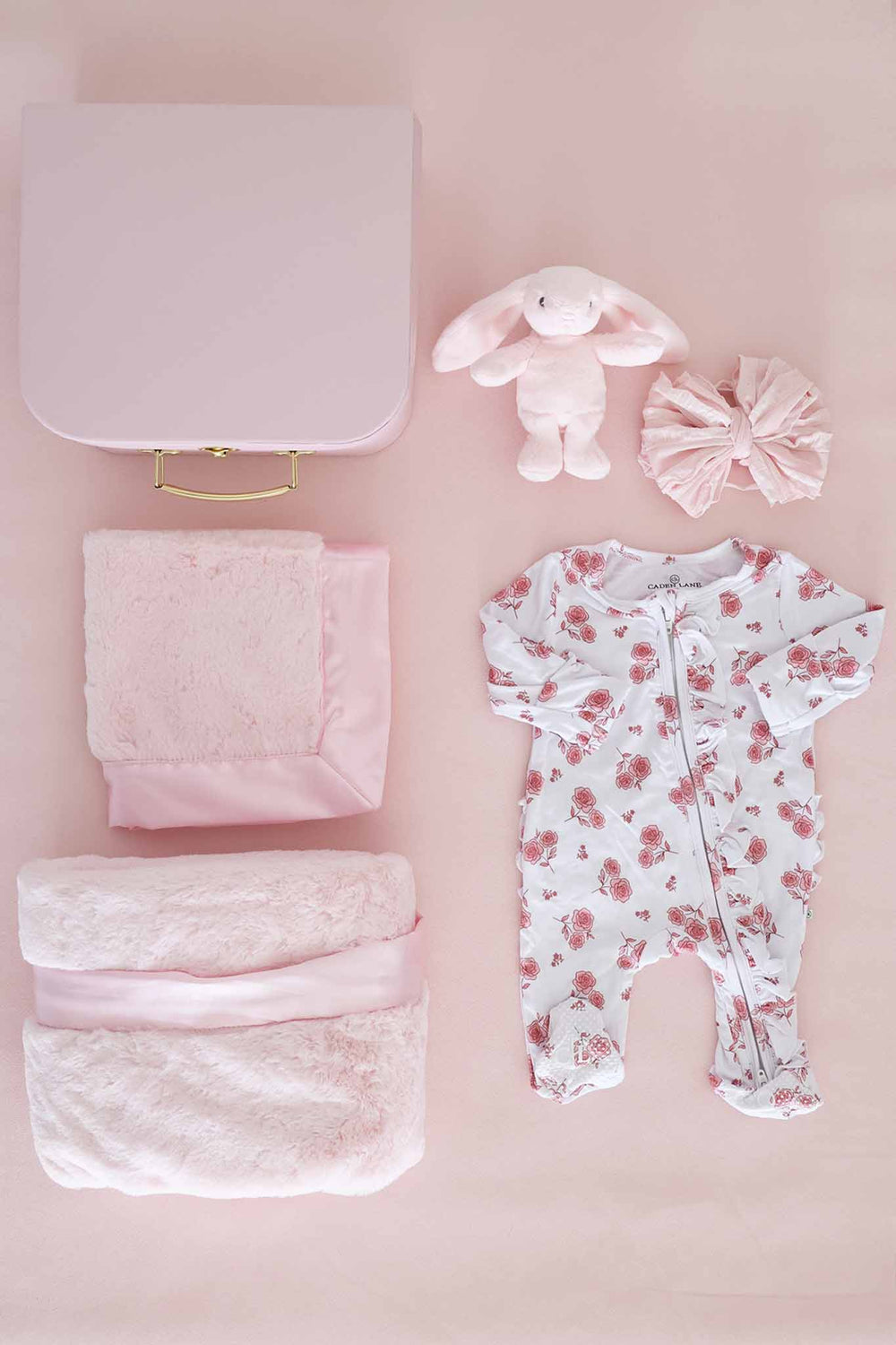 contents of newborn keepsake box with blanket, lovey, stuffed bunny, bow and floral footie