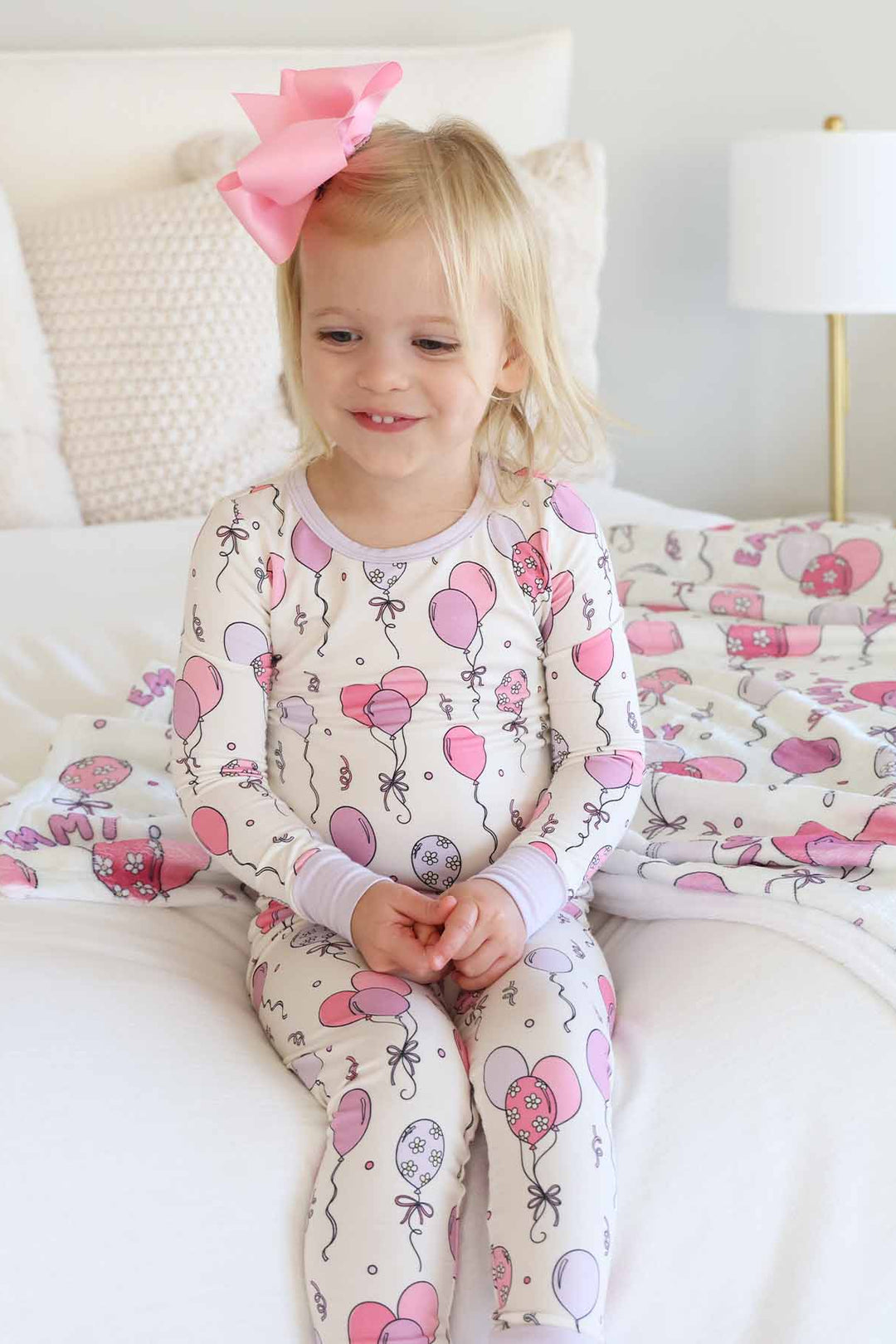 girl wearing party themed two piece pajama set with pink and purple balloons 