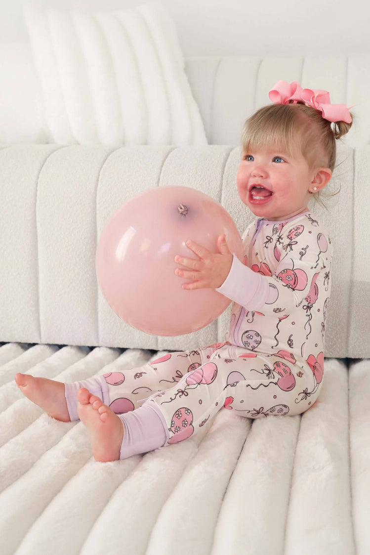 girl wearing a balloon convertible zip romper pajama holding a balloon 