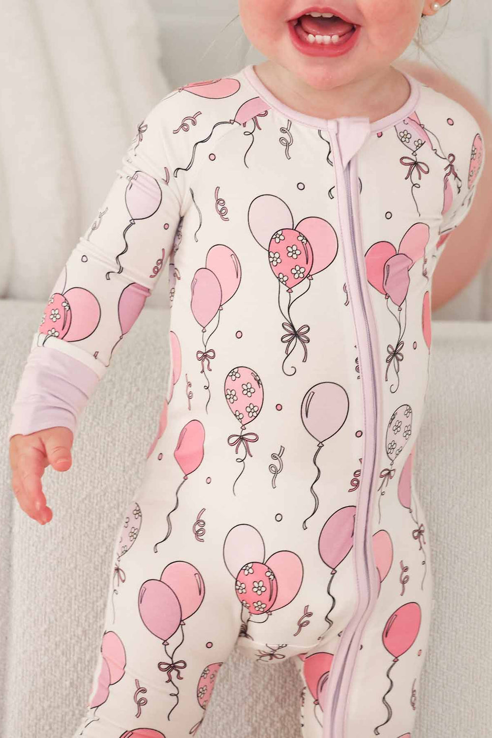 zip romper pajama with pink and purple balloons with daisies and streamers 