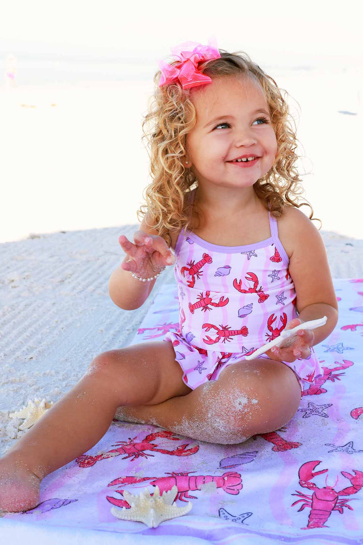 girl sitting on beach on personalized beach towel in pinch me two piece strappy tankini