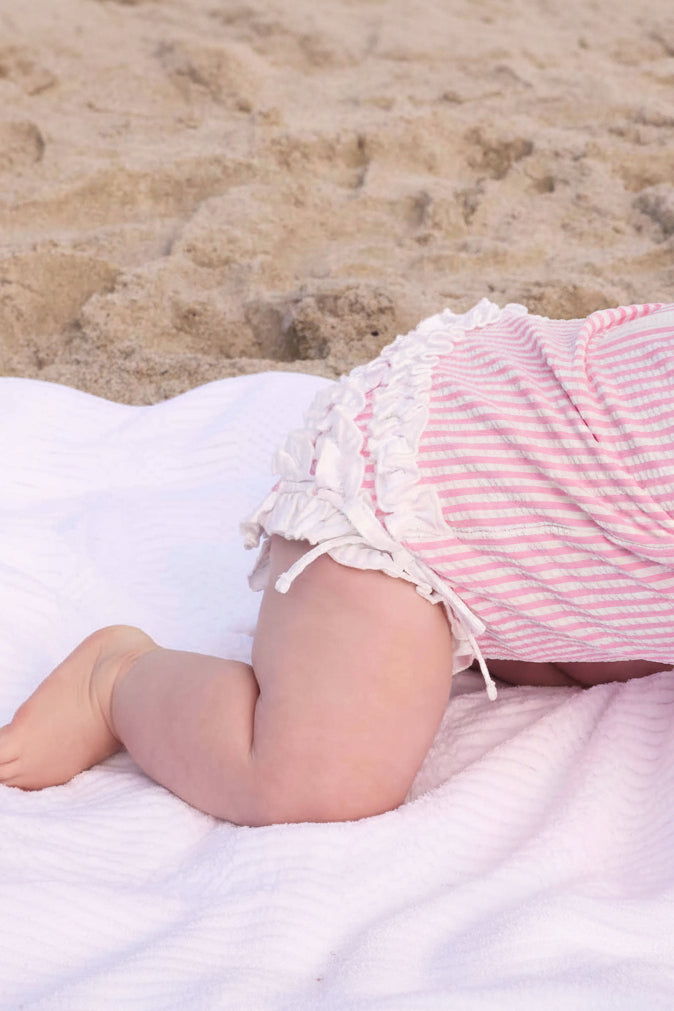 adorable baby rash guard in seersucker pink with ruffle accents for a stylish swim look