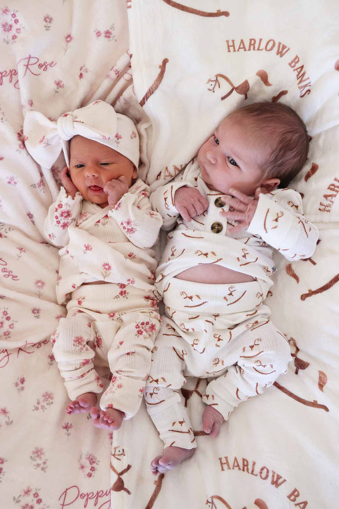 baby boy and girl in bamboo 2pc sherpa sets in flower and rocking horse prints laying on matching blankets