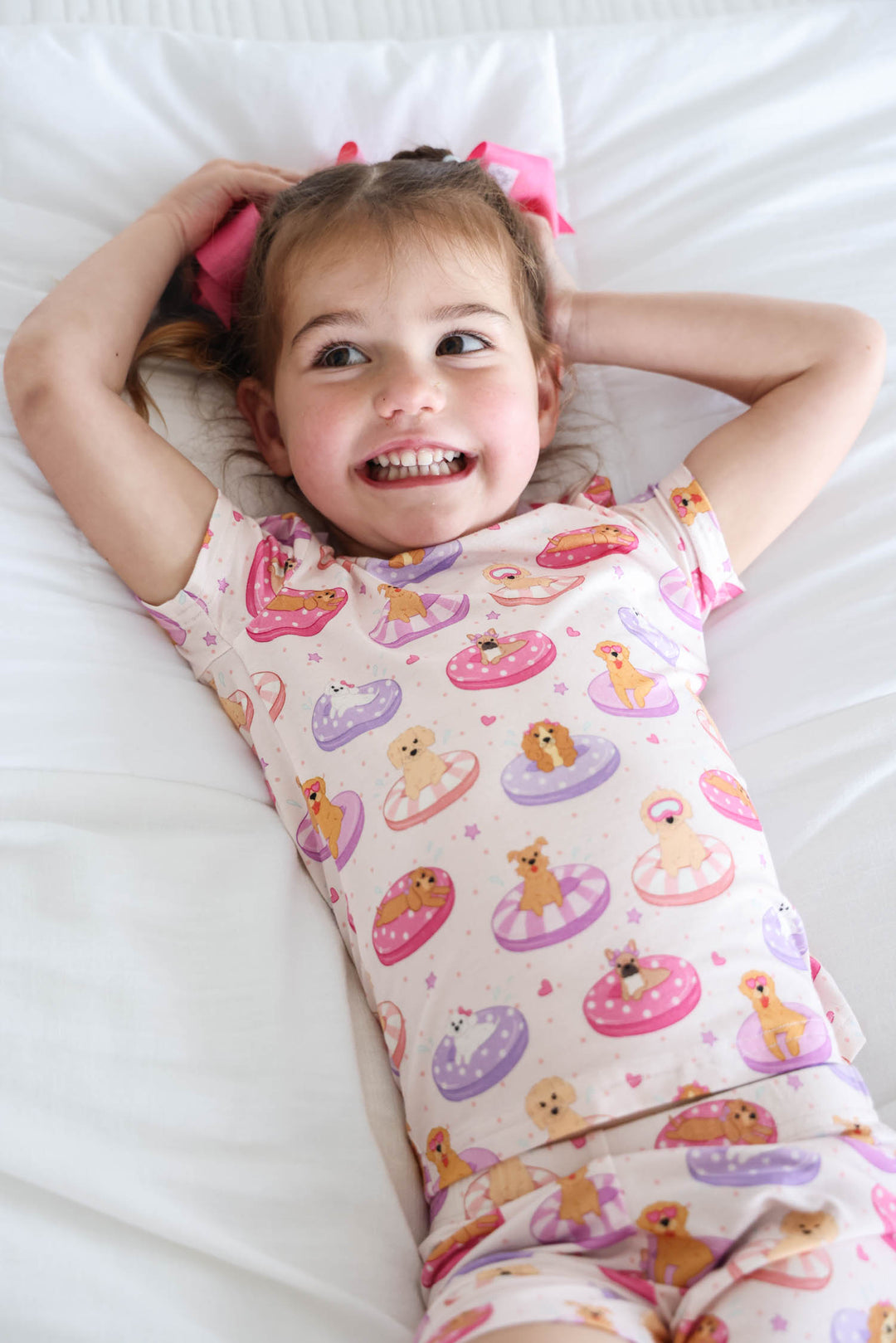 girl laying on bed in poolside pups pink two piece short pajama set