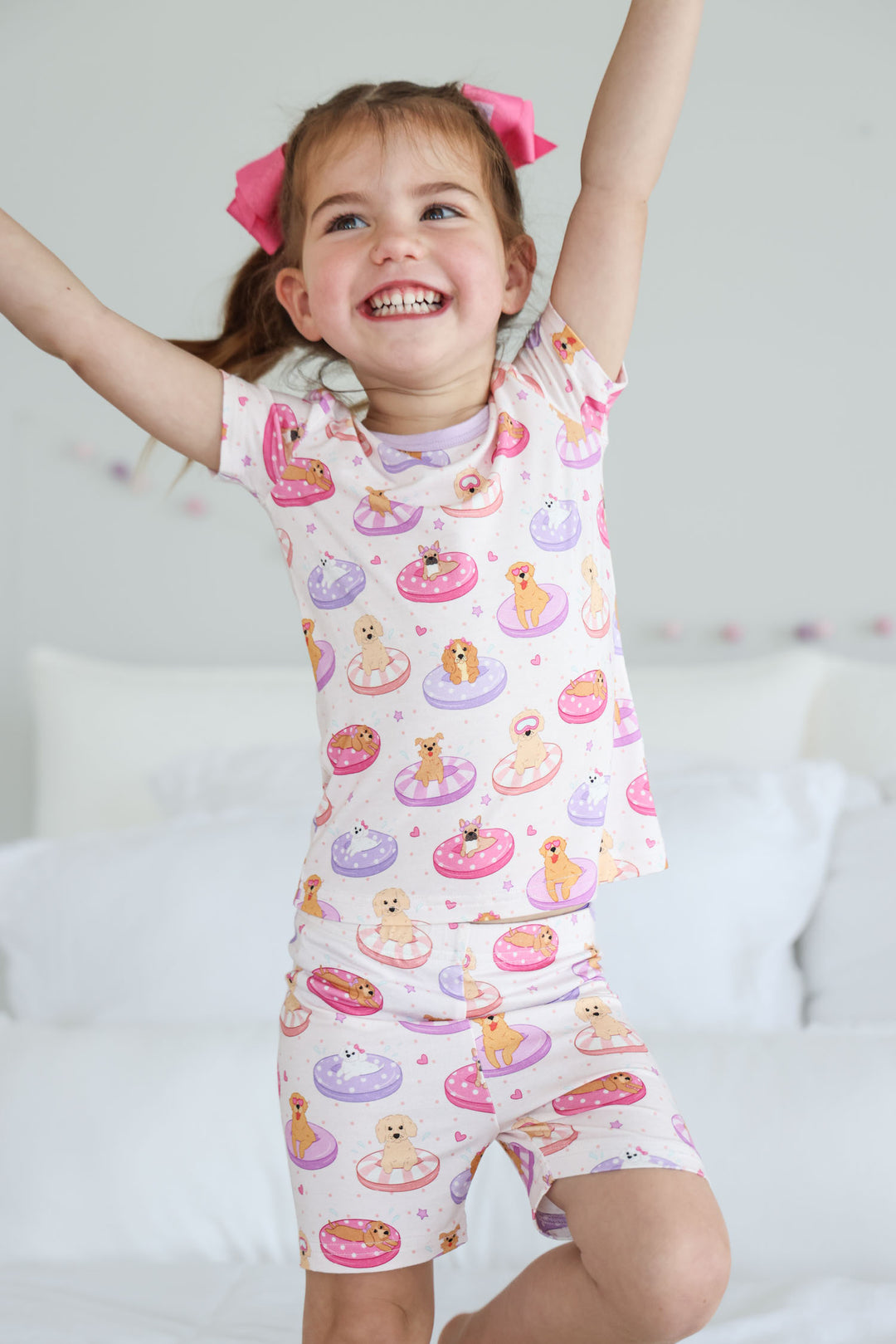 girl jumping wearing poolside pups pink two piece pajama set