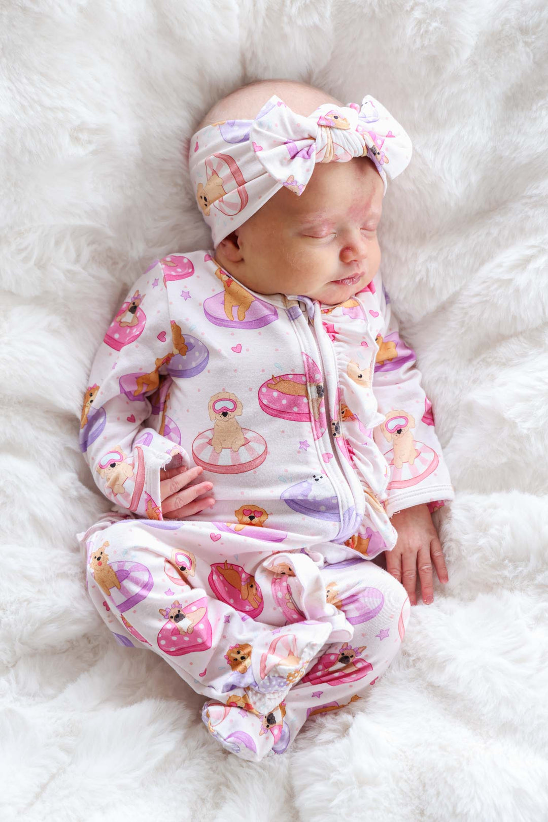 baby girl laying on back in poolside pups pink ruffle zipper footie pajama