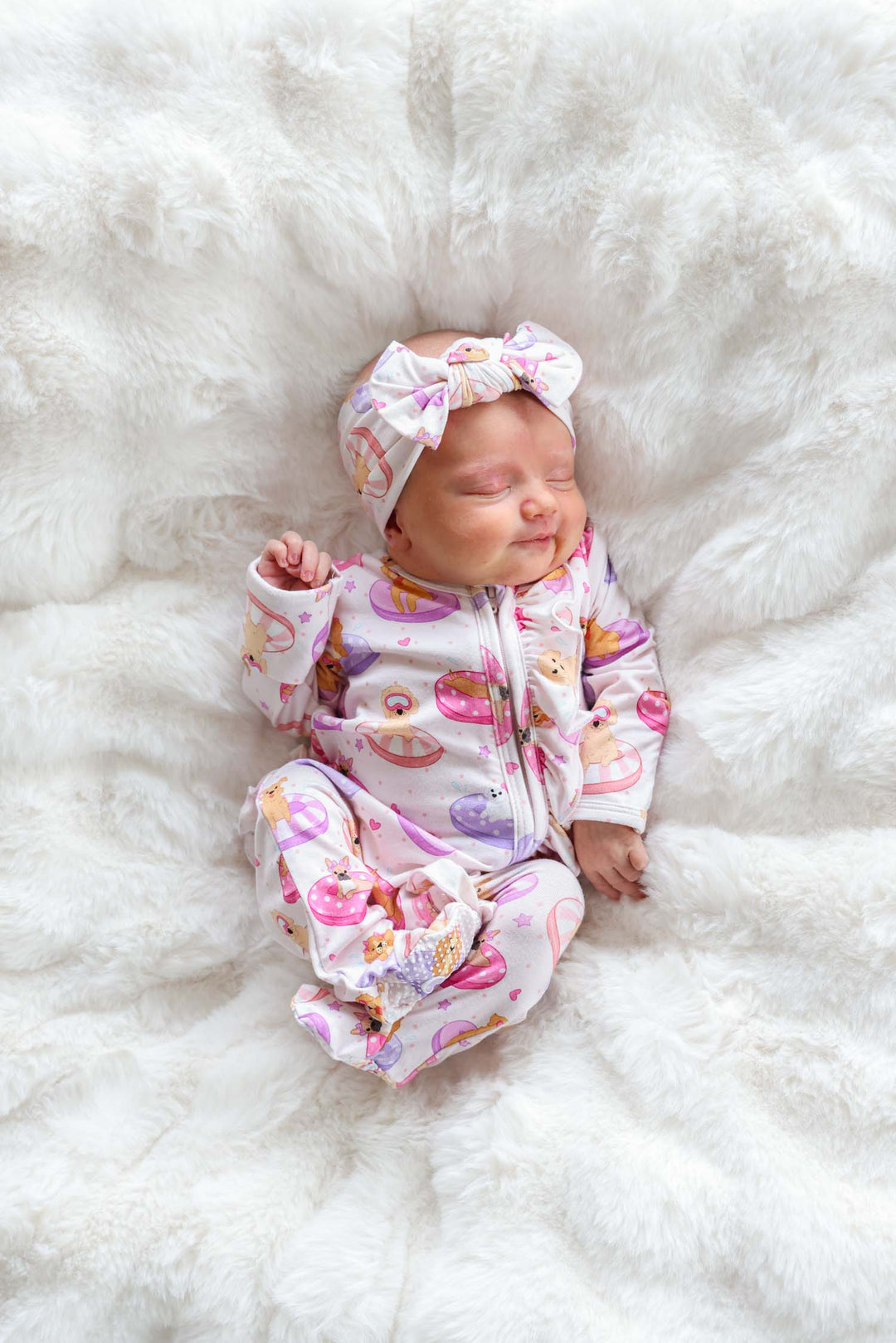 baby girl laying on blanket in poolside pups pink ruffle zipper footie with matching headwrap
