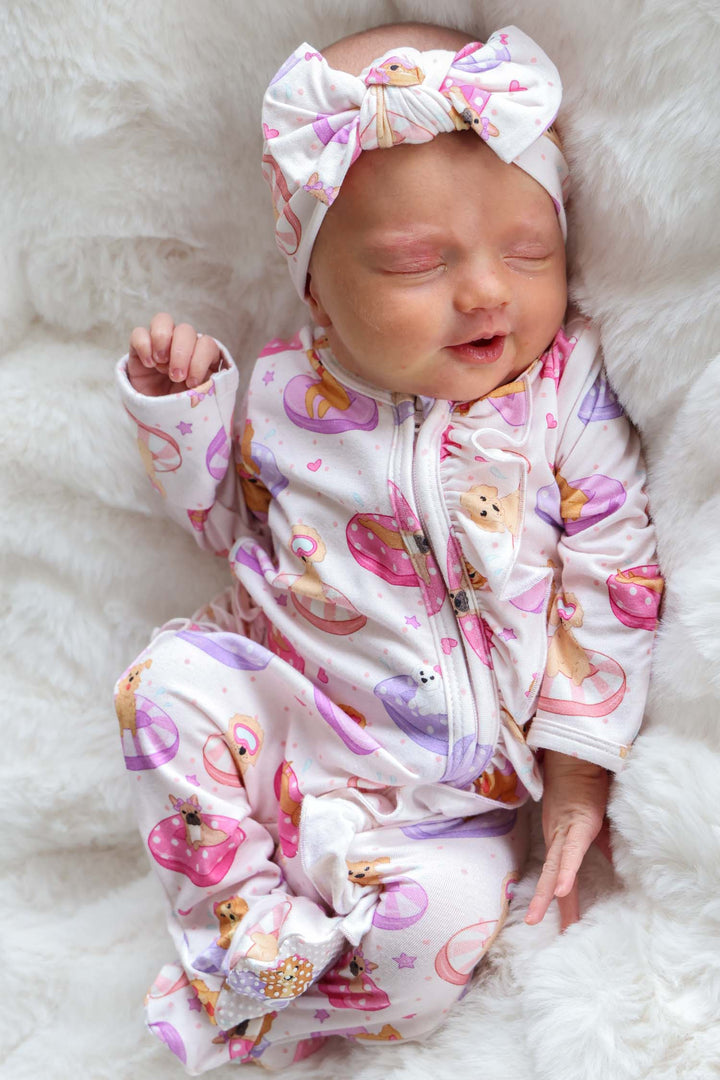baby girl laying on back in poolside pups ruffle zipper footie with matching headwrap