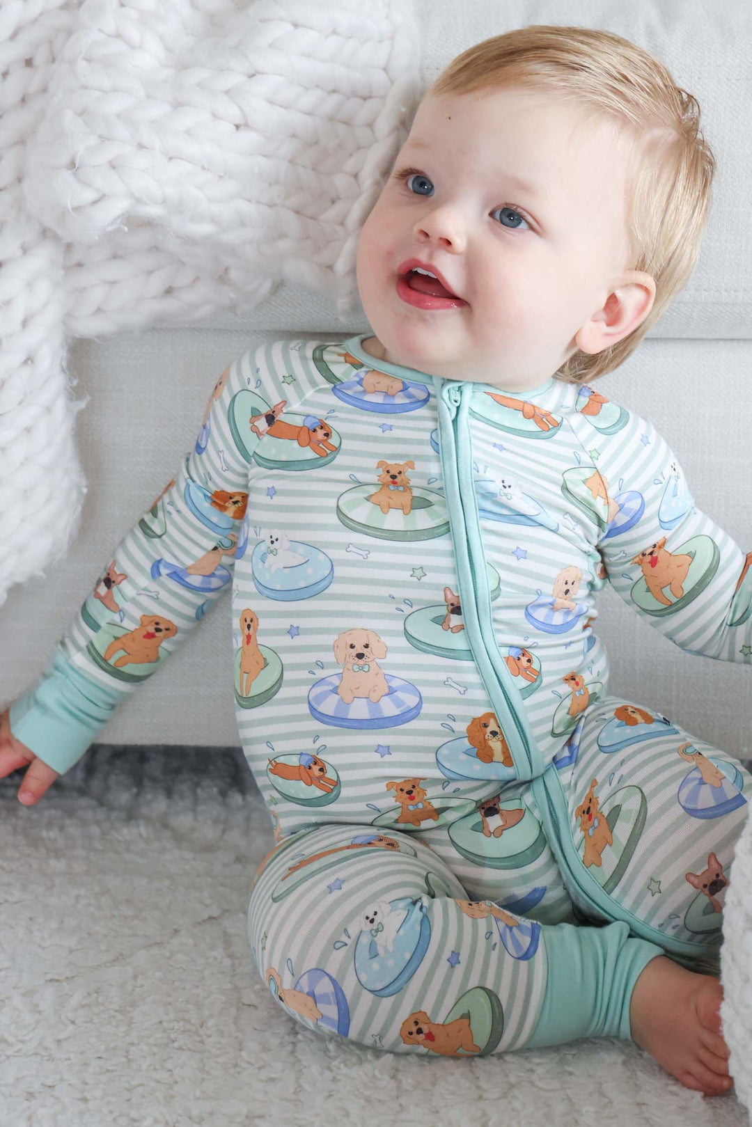 baby boy sitting on ground in poolside pups bamboo viscose pajama romper