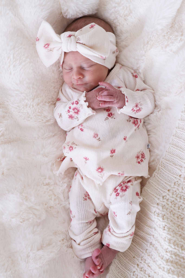 baby girl laying down wearing a vintage floral pointelle crossover set with matching headwrap