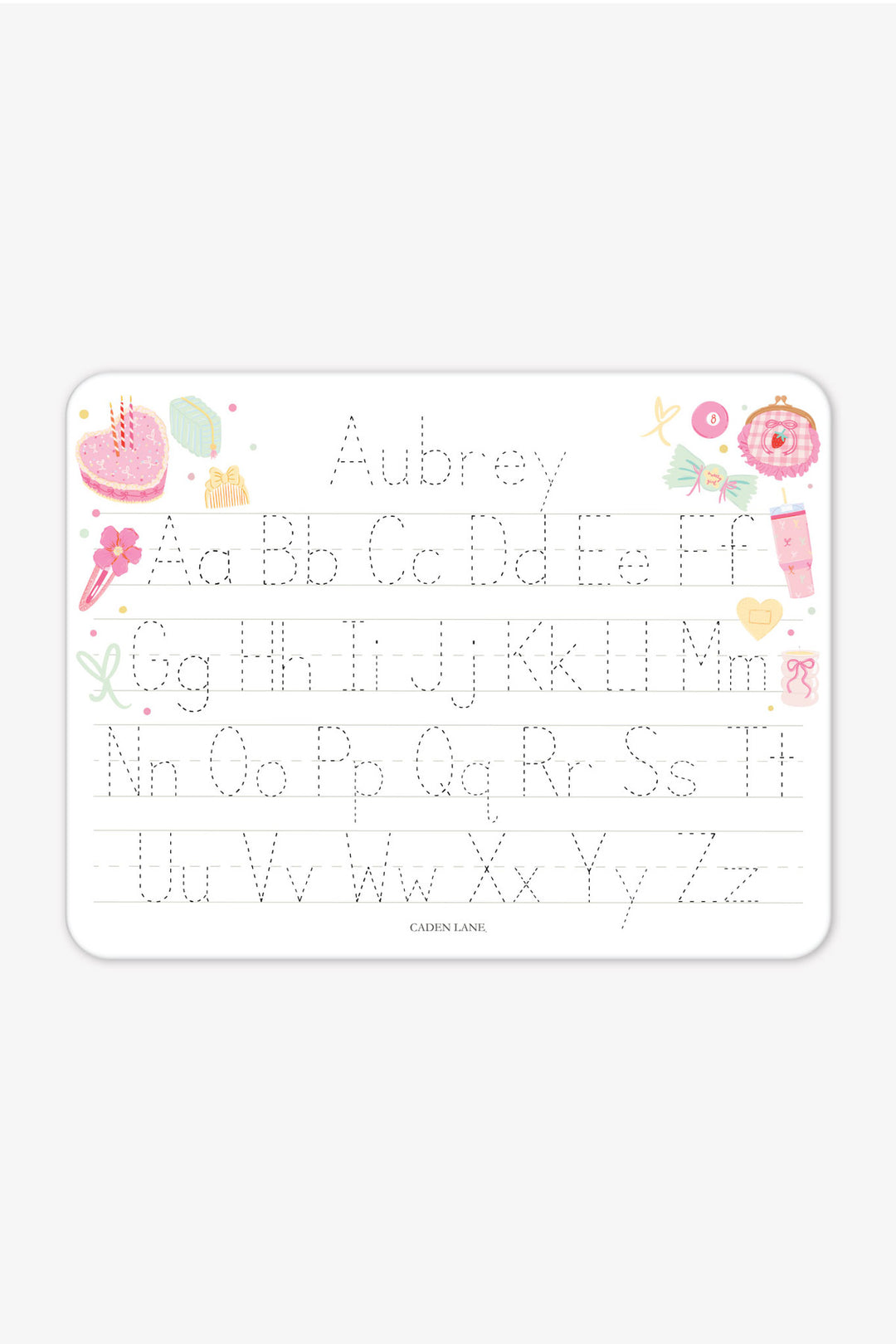 Flat lay of a personalized Caden Lane Pretty in Pink alphabet whiteboard, showing birthday cake, tumbler, and bows with tracing letters and custom name