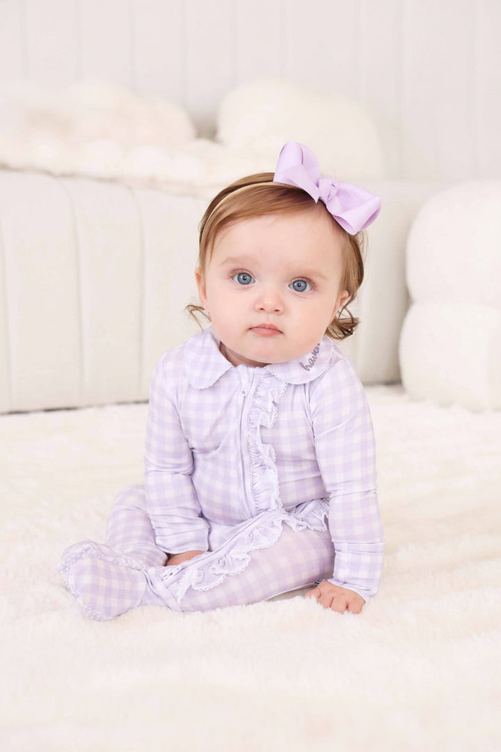 baby girl wearing light purple gingham print footie with lace trim and embroidered peter pan collar