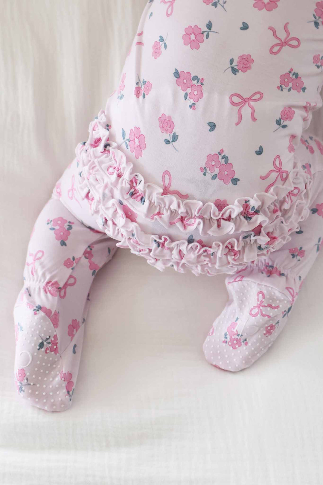 closeup of ribbon and roses pink ruffle bottom zipper footie for baby girls 