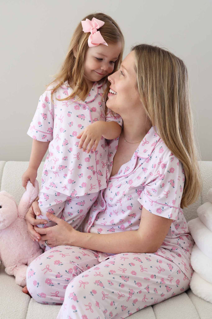 mom and daughter sitting next to each other on couch in pink ribbon and roses matching lounge sets 