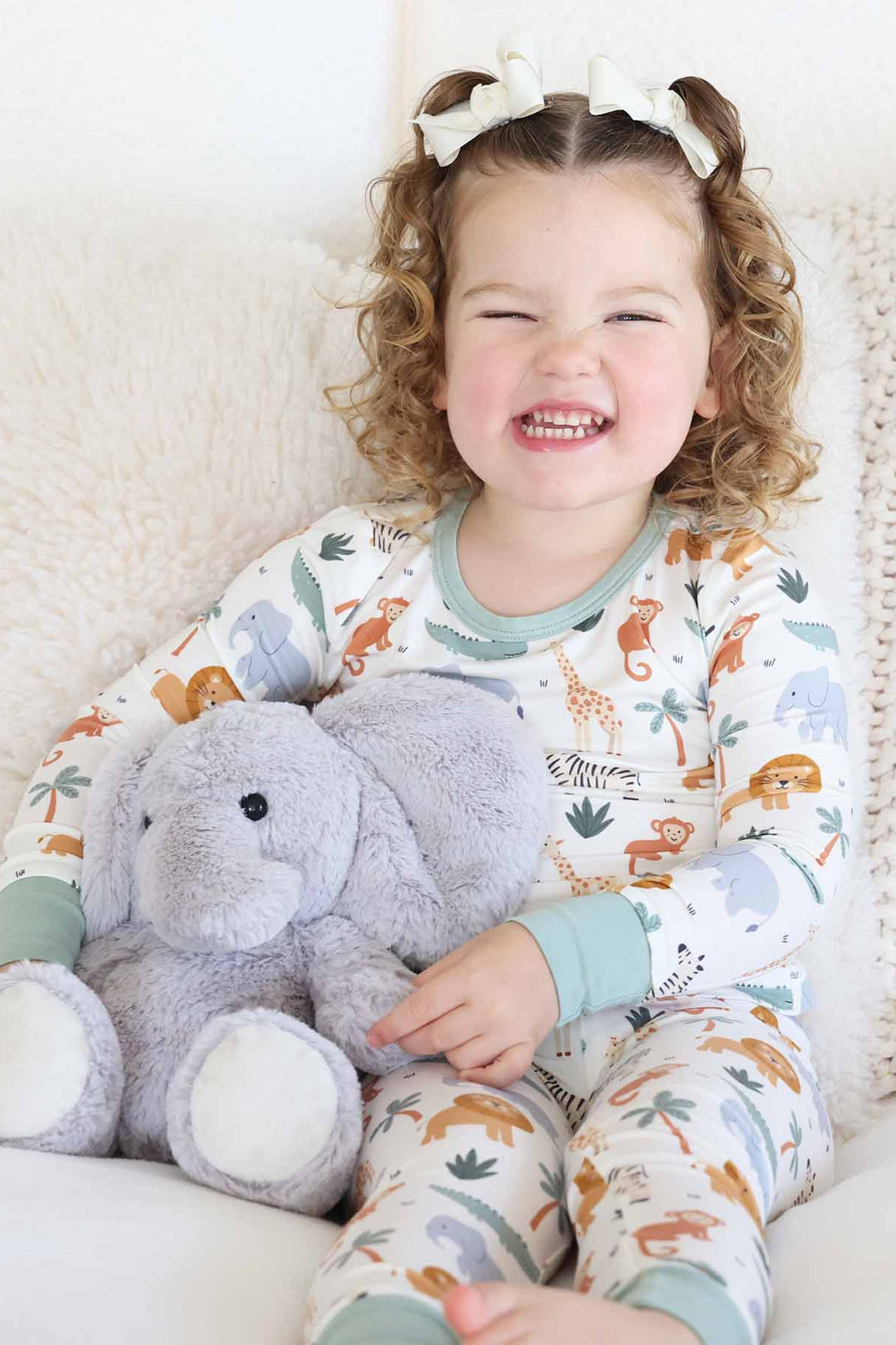 girl wearing safari themed two piece pajama set with elephant stuffed animal