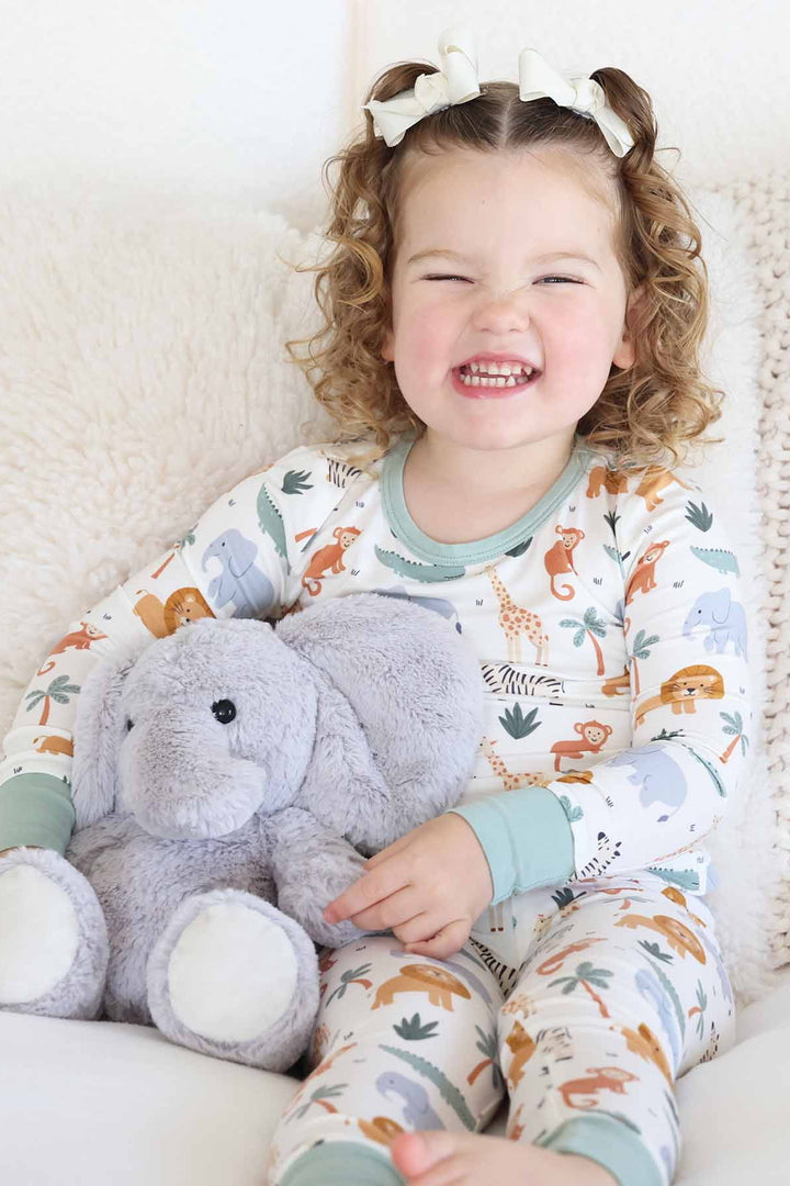 girl wearing safari themed two piece pajama set with elephant stuffed animal