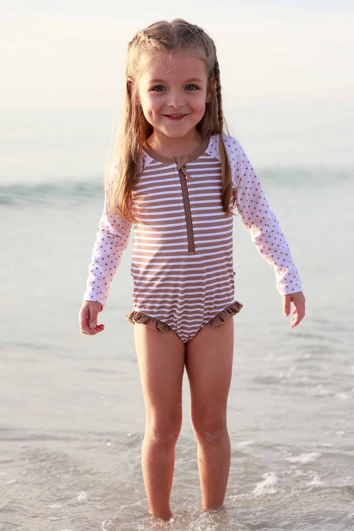 girl playing in ocean wearing sandy stripes front zip rash guard romper swimsuit 