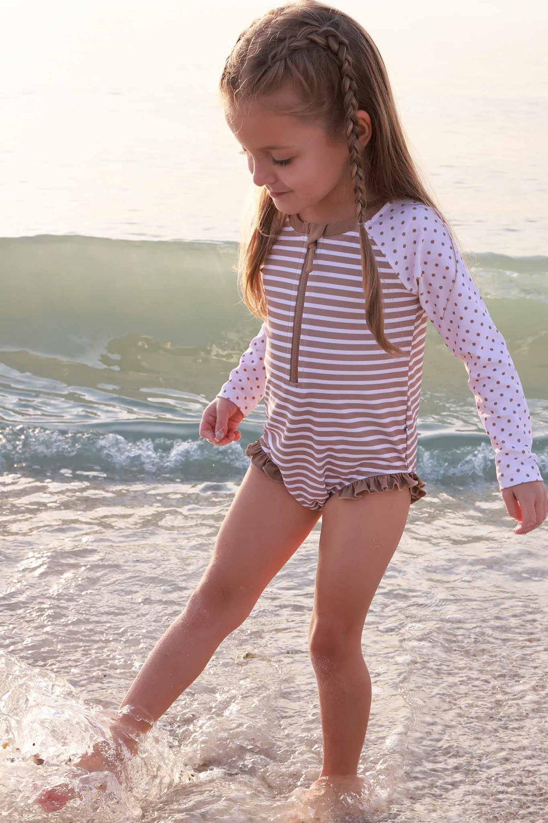 girl playing in ocean wearing sandy stripes long sleeve rash guard romper with front zipper 