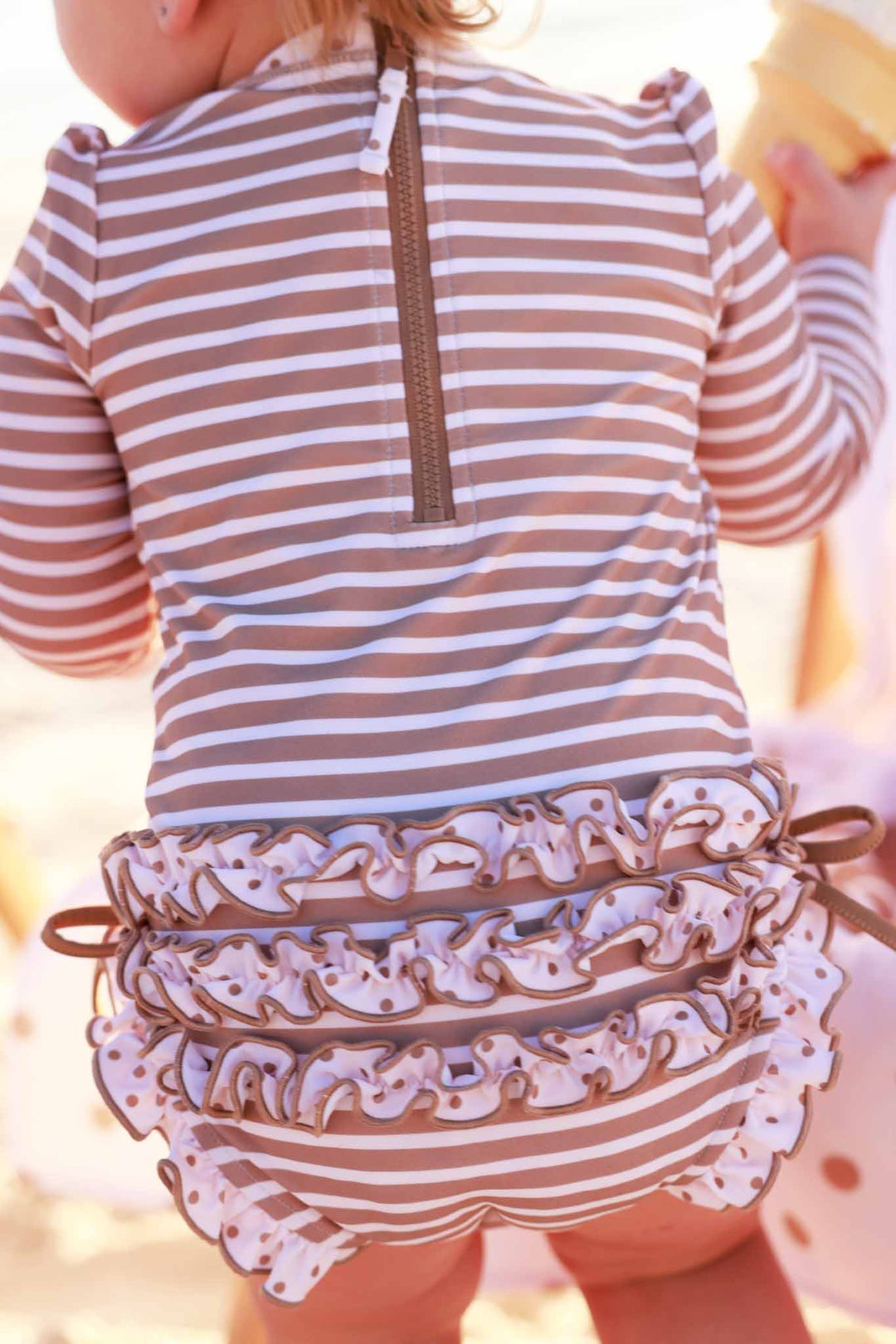 long sleeve rash guard swimsuit for girls with brown and white stripes and polka dot accents 