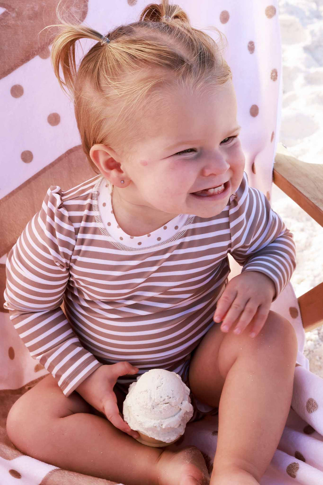 smiling girl in sandy stripes ruffle bottom rash guard swim romper 