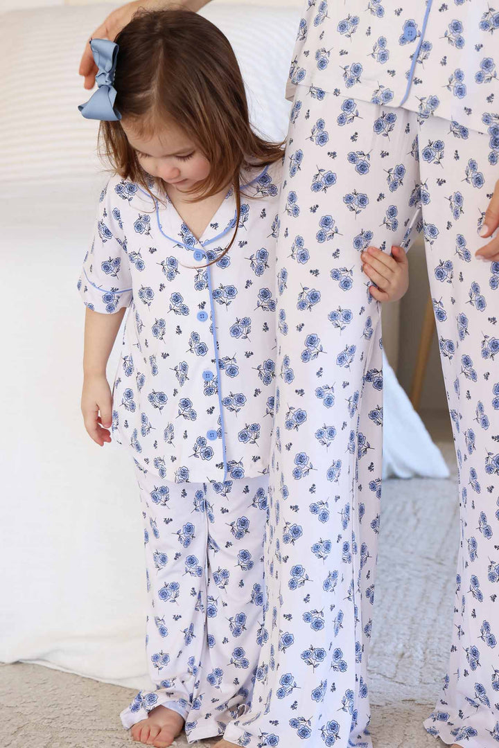 girl wearing a blue rose collared lounge set holding onto mom's leg in matching pants 