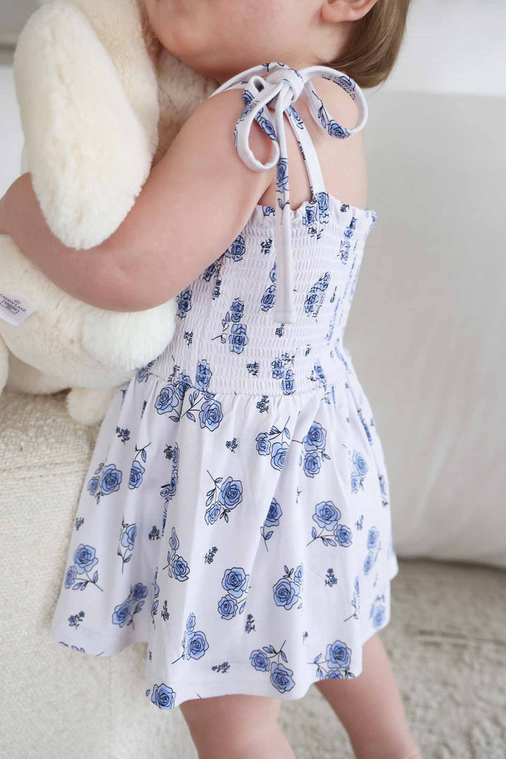 baby girl wearing smocked top bow shoulder bodysuit with skirt in blue rose print 
