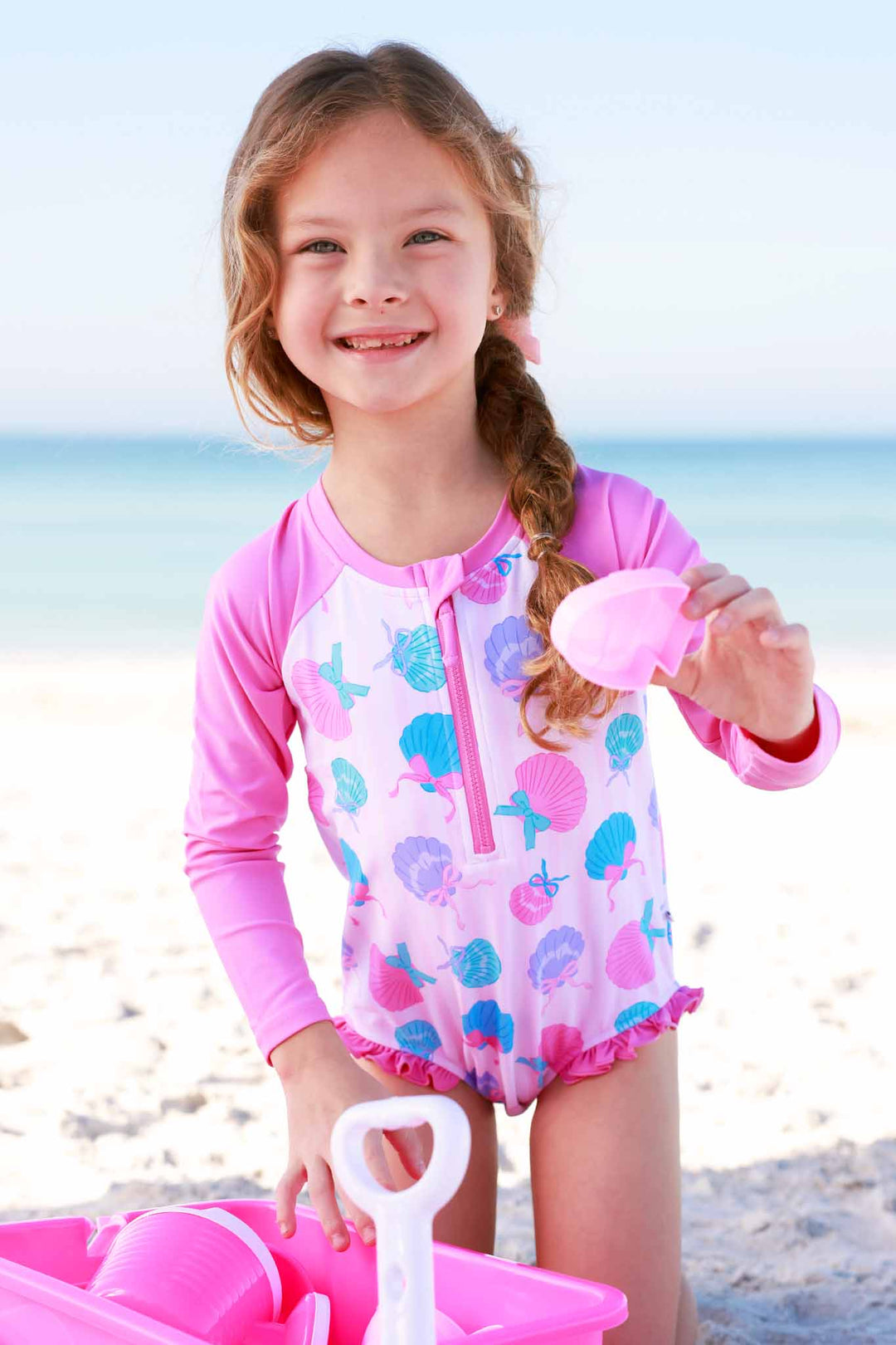 girl playing with beach toys in seashell long sleeve rash guard swimsuit 
