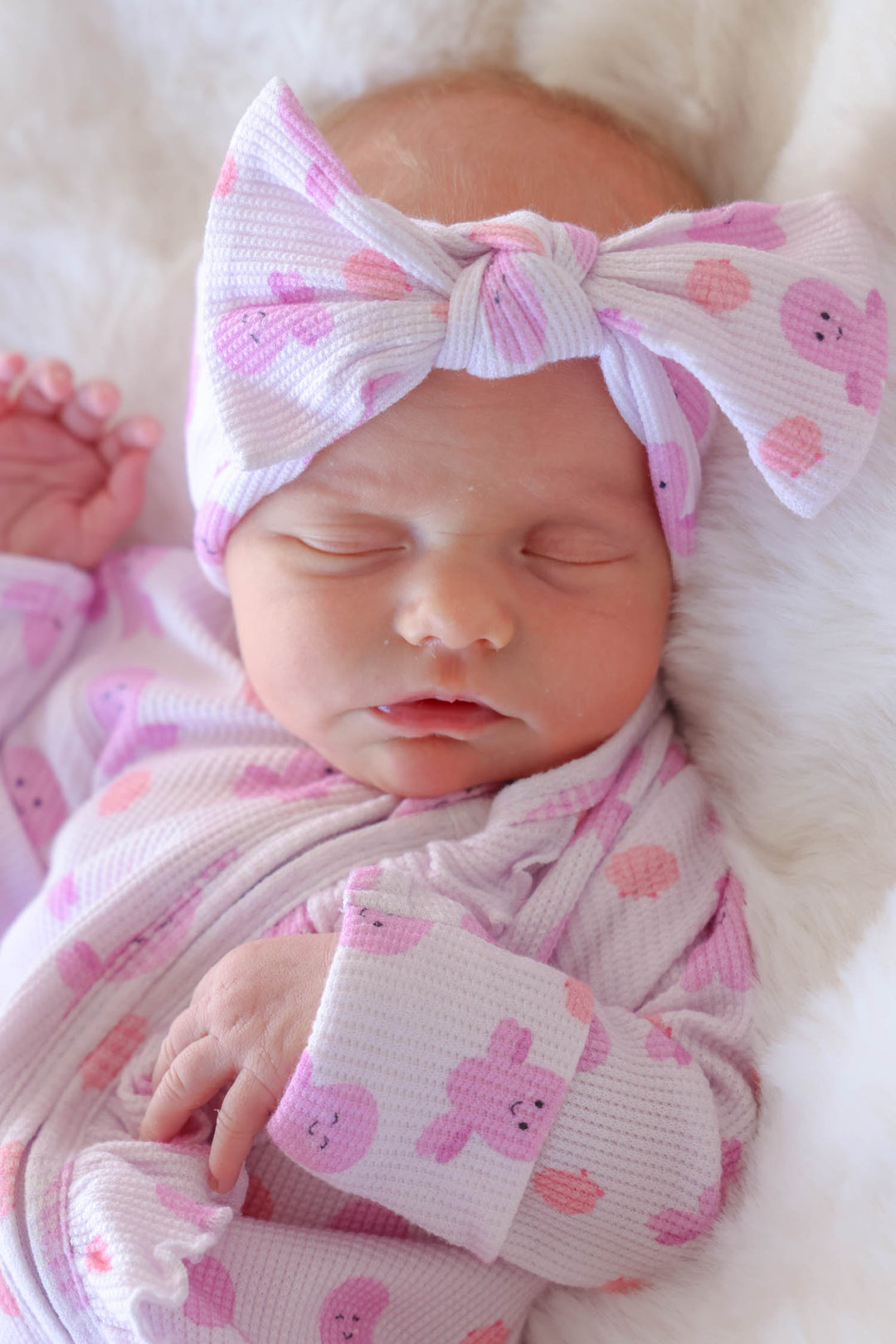 close-up portrait of newborn wearing sea snuggles bamboo waffle knit large bow headwrap with matching ruffle zipper footie