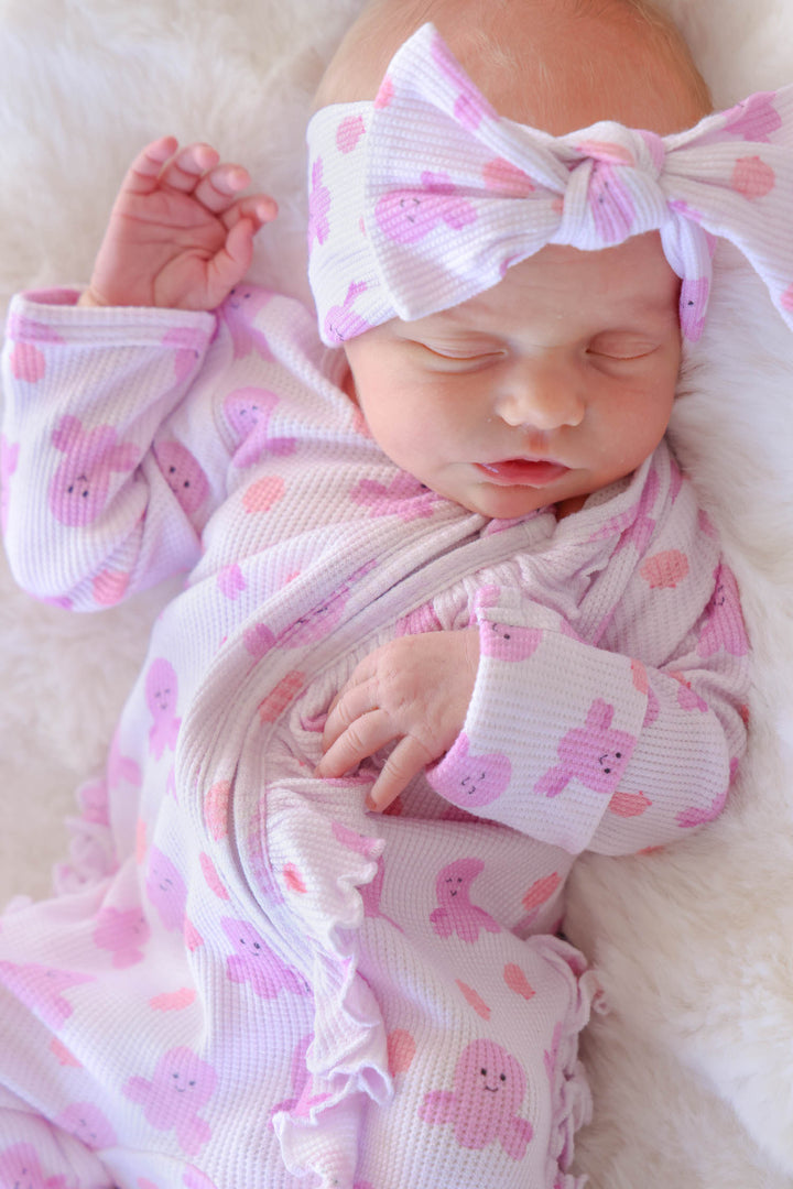 sleeping newborn in sea snuggles bamboo waffle ruffle zipper footie wearing matching bamboo waffle knit large bow headwrap