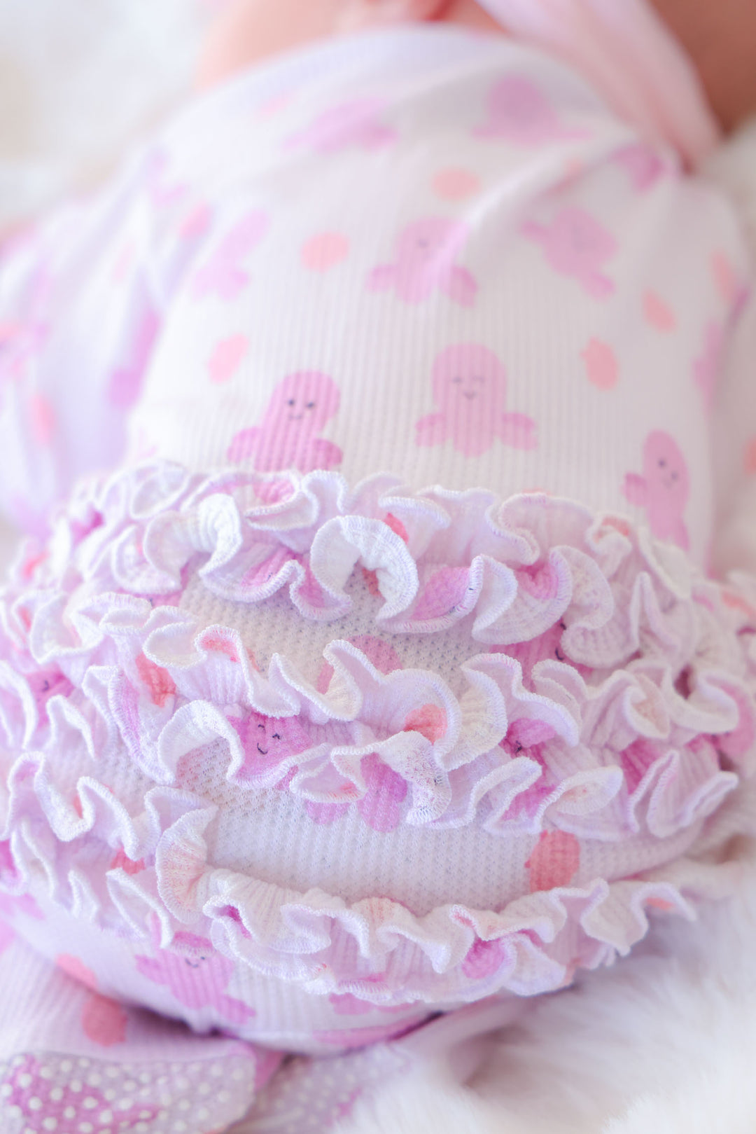 close-up detail of layered ruffle trim on sea snuggles bamboo waffle ruffle zipper footie for newborns
