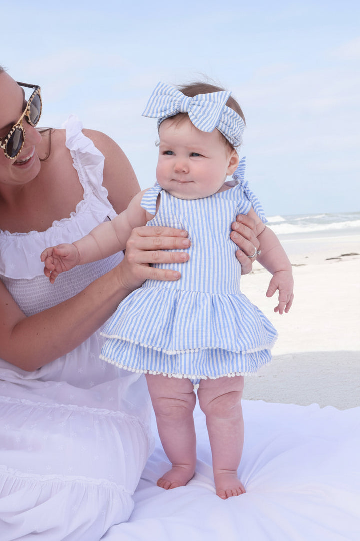 baby and toddler tiered skirt in seersucker blue with pom trim and matching bow headwrap