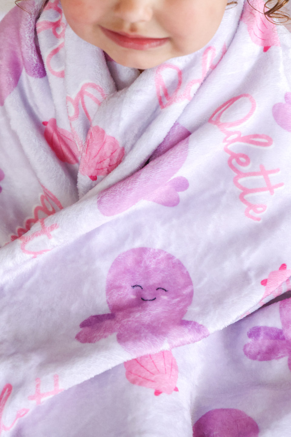 close-up of personalized sea snuggles kids blanket showing soft plush texture with octopus print and custom name in pink script