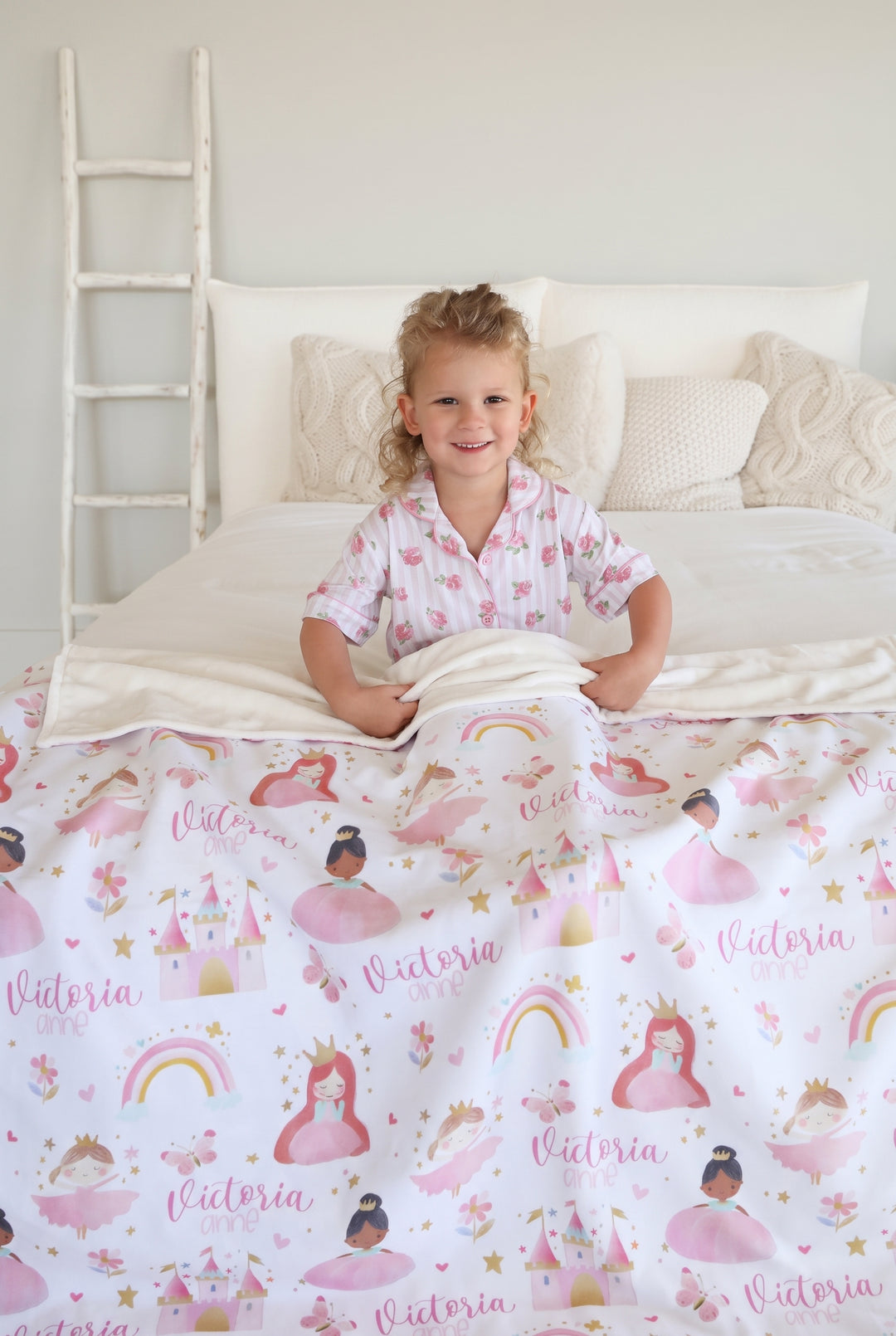 little girl wrapped in a caden lane personalzied themed blanket, featuring princesses and castles. 