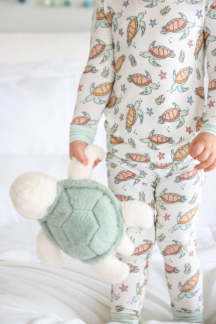 boy wearing turtle and starfish pajamas holding a stuffed turtle 