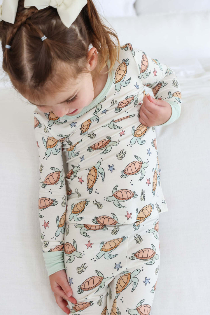 lifestyle photo of baby in turtley rad turtle print bamboo two piece pajamas