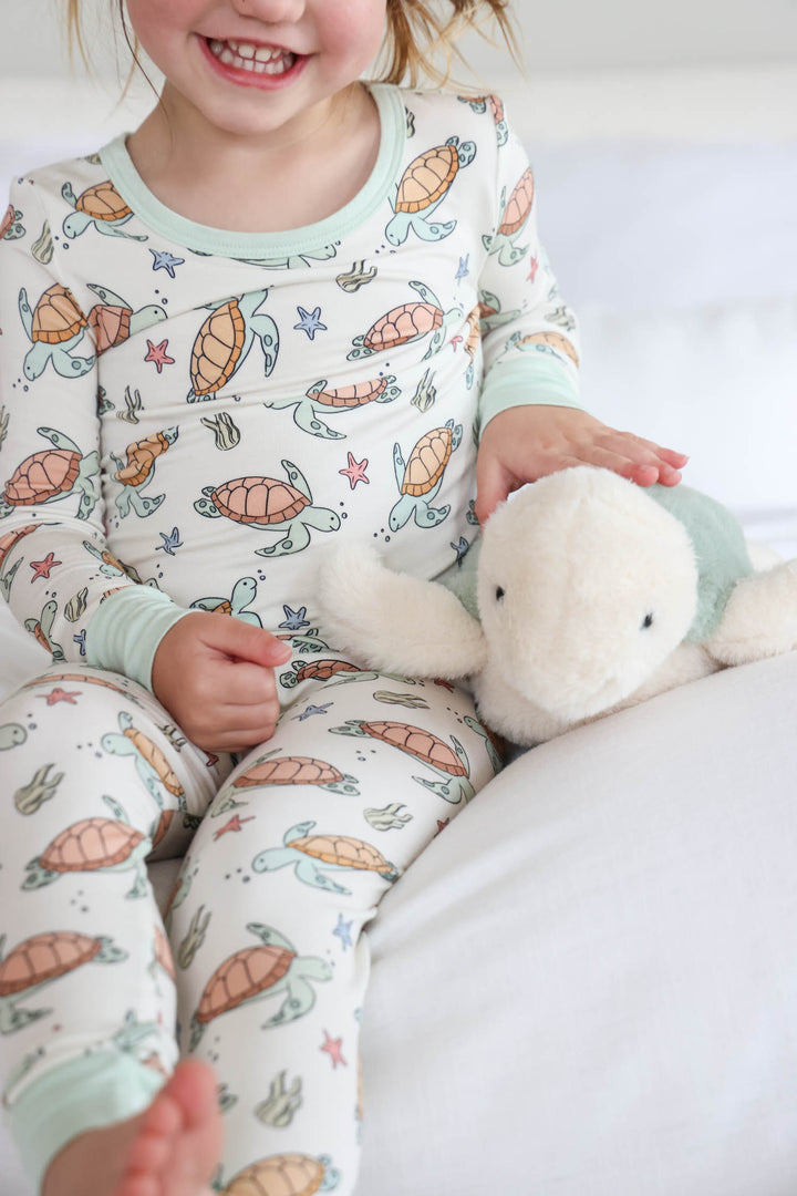 lifestyle photo of baby in turtley rad turtle print bamboo two piece pajamas