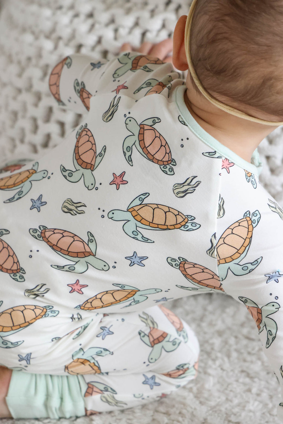lifestyle photo of baby in turtley rad turtle print bamboo convertible zip romper