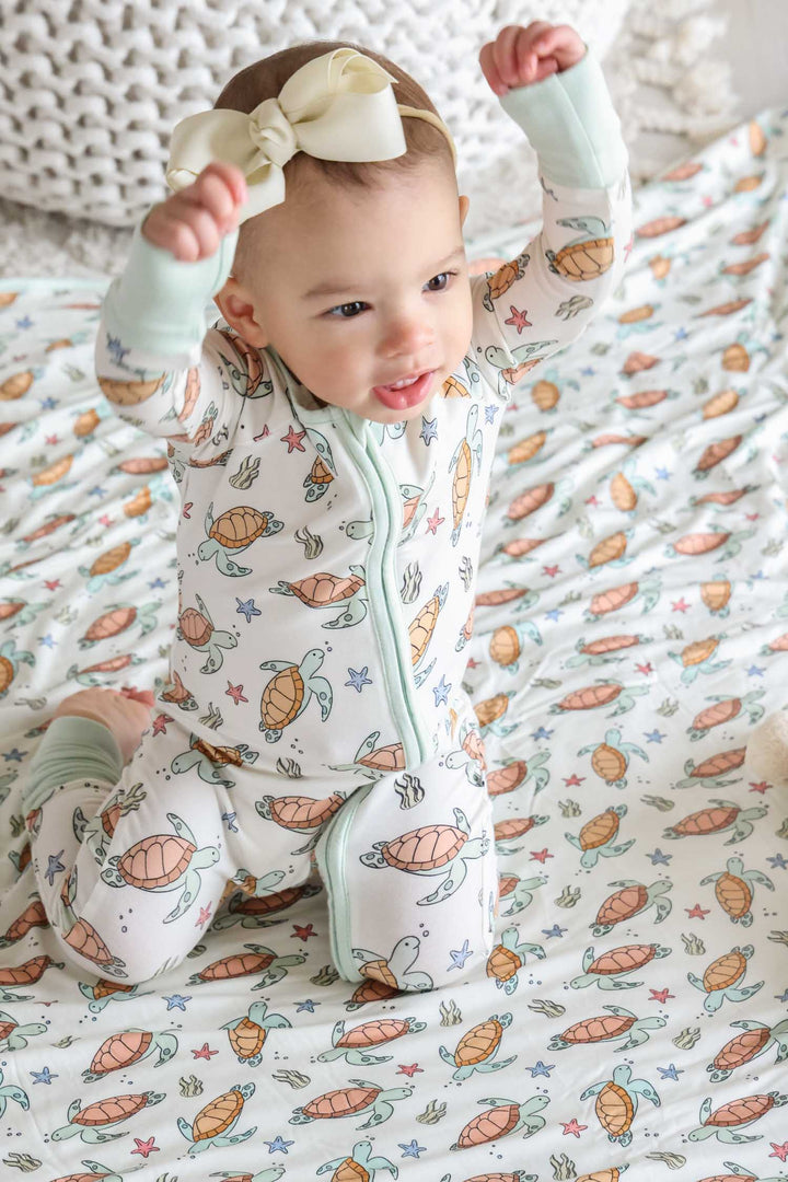 lifestyle photo of baby in turtley rad turtle print bamboo convertible zip romper