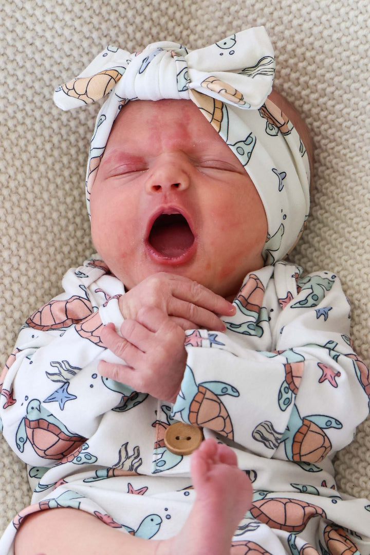 lifestyle photo of baby in turtley rad turtle print bamboo knot gown