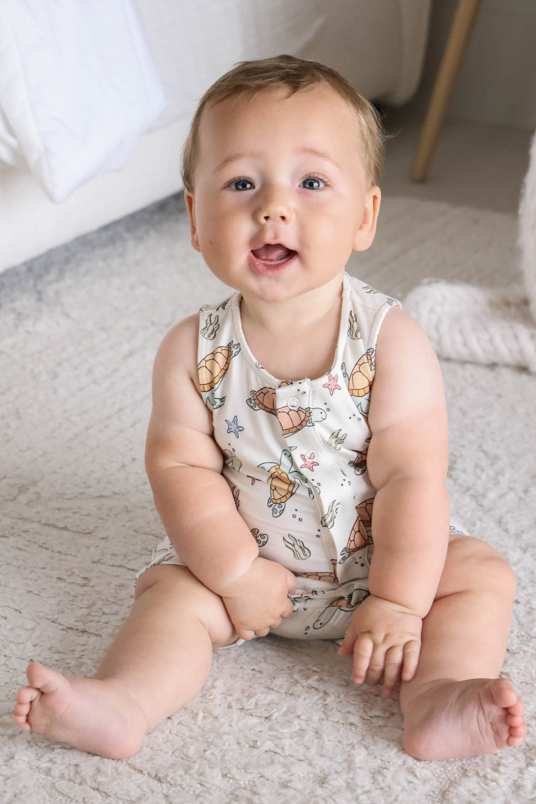 lifestyle photo of baby in turtley rad turtle print bamboo sleeveless snap romper