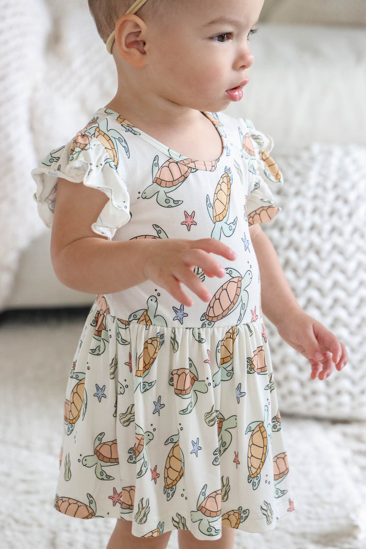 lifestyle photo of baby in turtley rad turtle print bamboo smocked twirl one piece