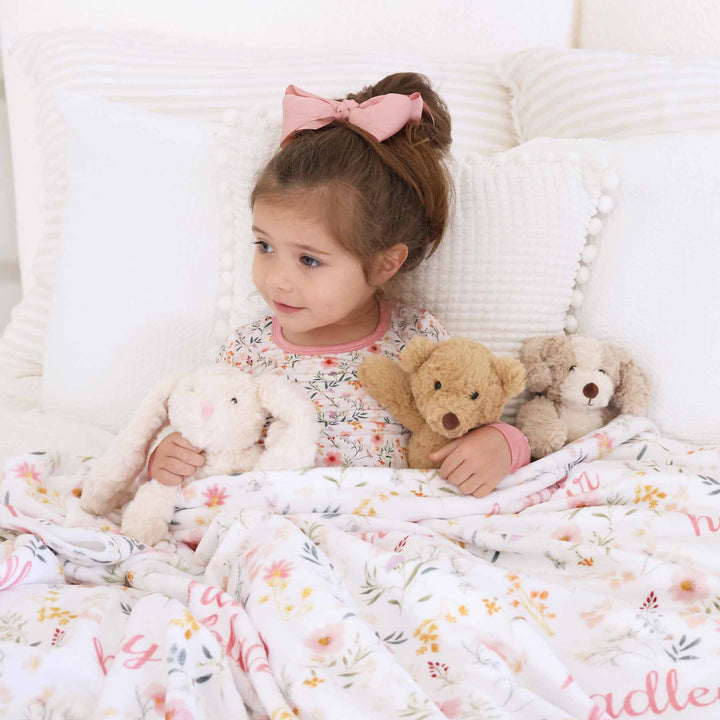 girl wearing dainty floral printed pajamas with matching personalized blanket 